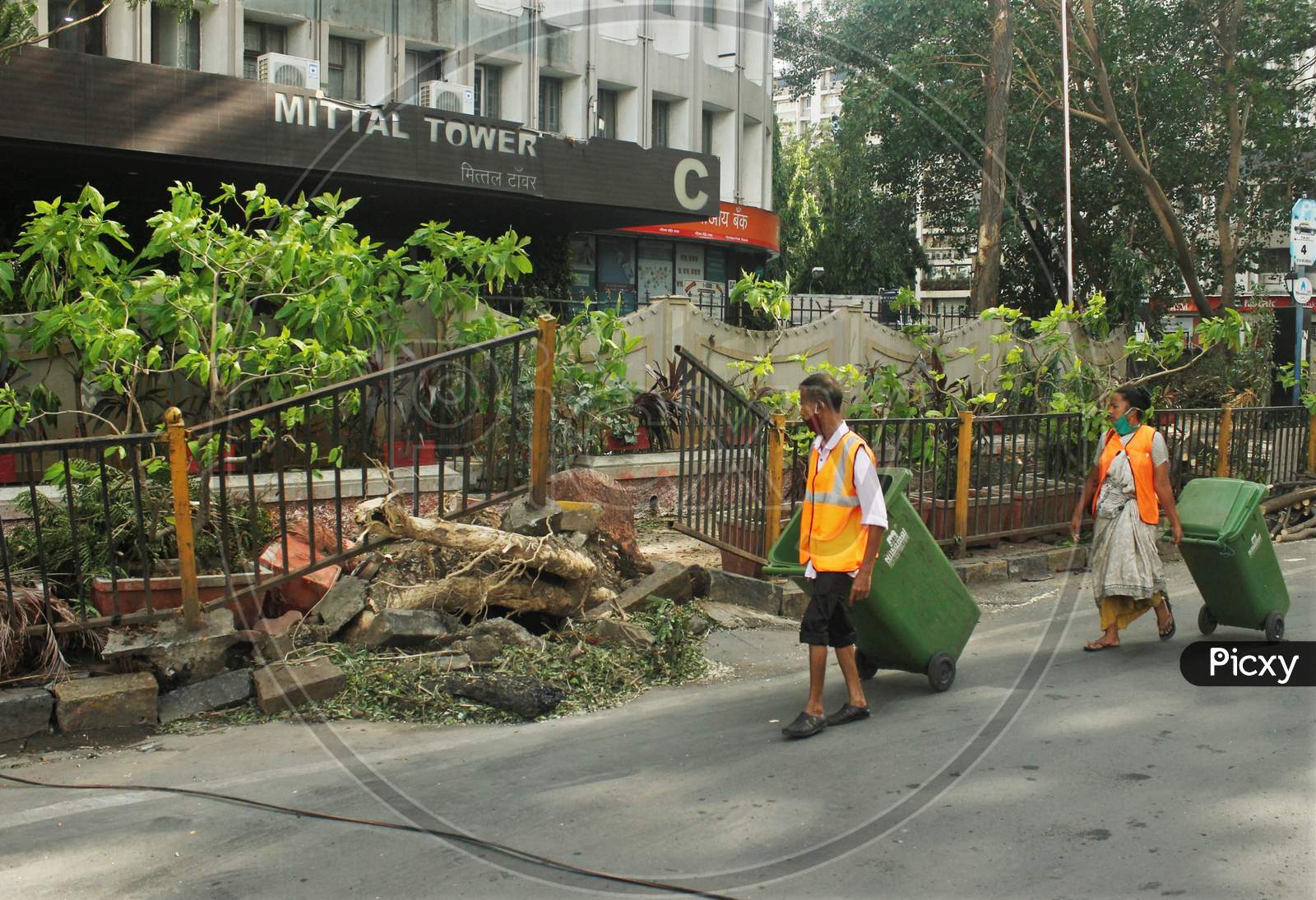 BMC workers walk past an uprooted pavement railing, after cyclone Nisarga made its landfall on June 3, on the outskirts of the city, in Mumbai, India, June 5, 2020.