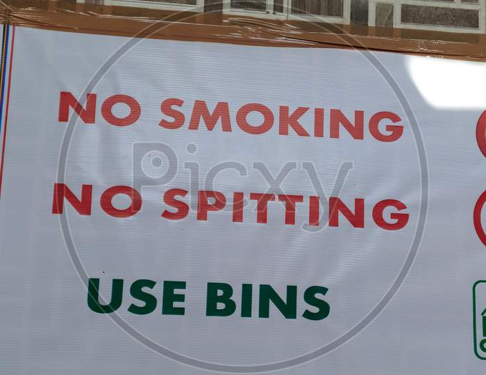 A display board of No Smoking, No spitting and use bins on the wall.