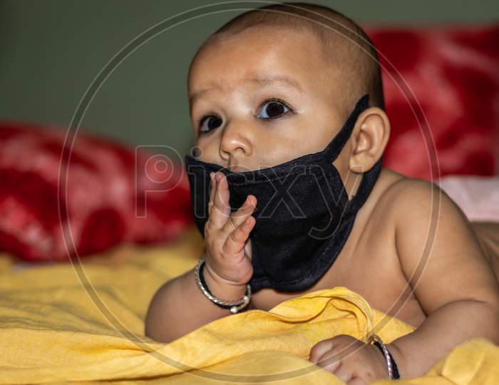 Child Wearing Black Mask For Protection Against Infections With Background Blur