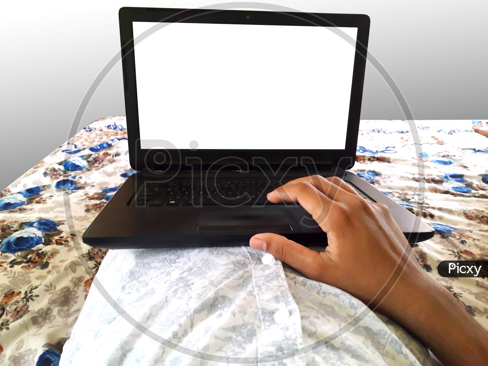 A Male Doing Work On Black Laptop Lying Down On Bed White Screen Mockup For Work From Home