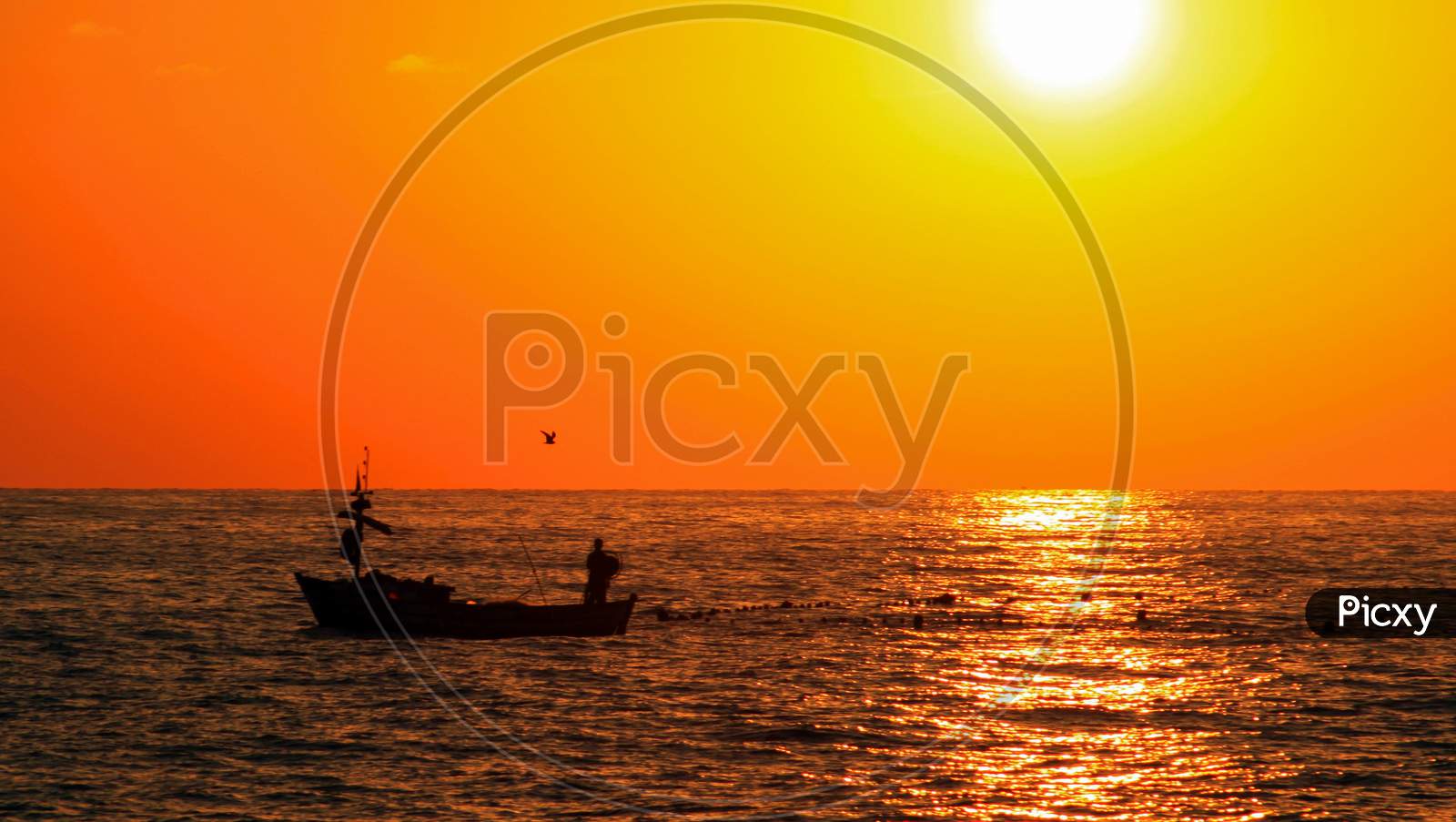 Fisherman In Boat On The Sea Before Sunset