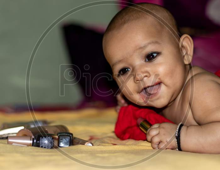 Baby Infant Cute Holding Lipstick With Blurred Background