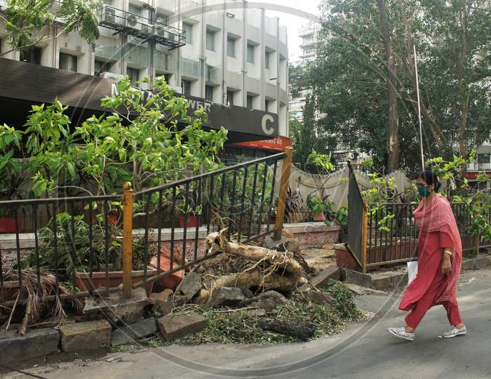 A woman walks past an uprooted pavement railing, after cyclone Nisarga made its landfall on June 3, on the outskirts of the city, in Mumbai, India, June 5, 2020.