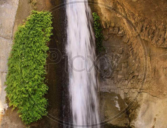Vertical Waterfall With Green Plants On The Side