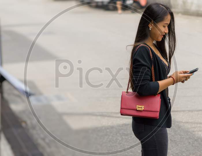 Pattaya,Thailand - October 19,2019:Soi Buakhaow A Young,Beautiful Thai Woman Was Checking Her Phone For New Messages.