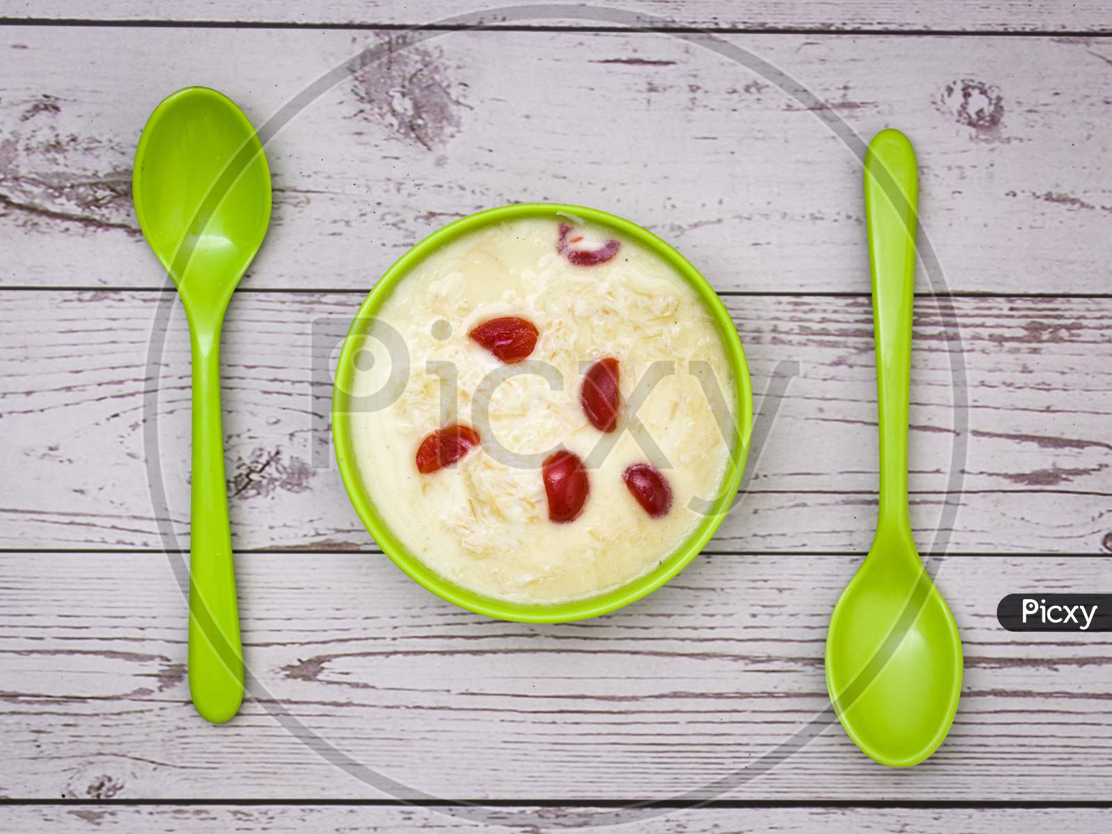 Sewai or kheer consumed on eid or indian festivals. Served with red cherry toppings in a green bowl.