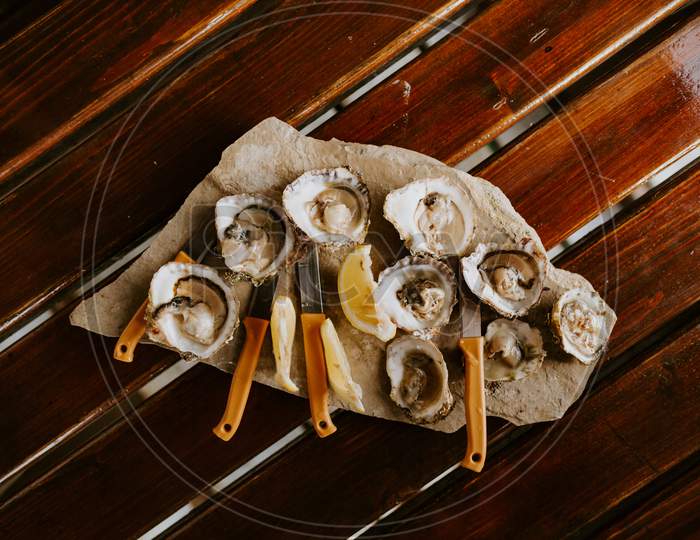 Fresh Oysters Eating With Lemon On Wooden Table