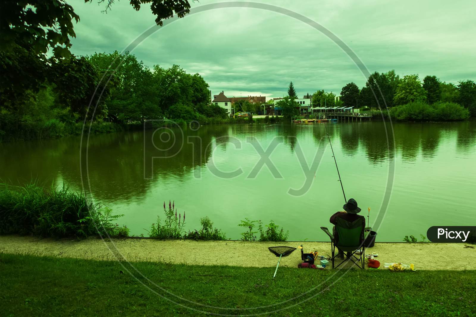 An Angler Was Fishing On A Small Lake On A Cloudy Afternoon