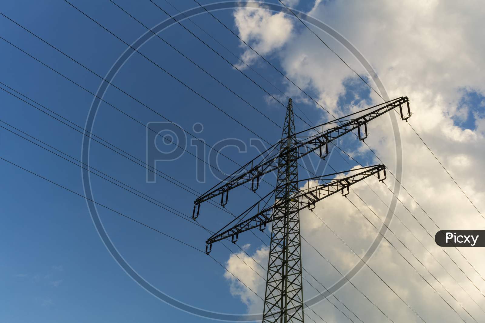 A Power Mast Below A Blue,Cloudy Sky