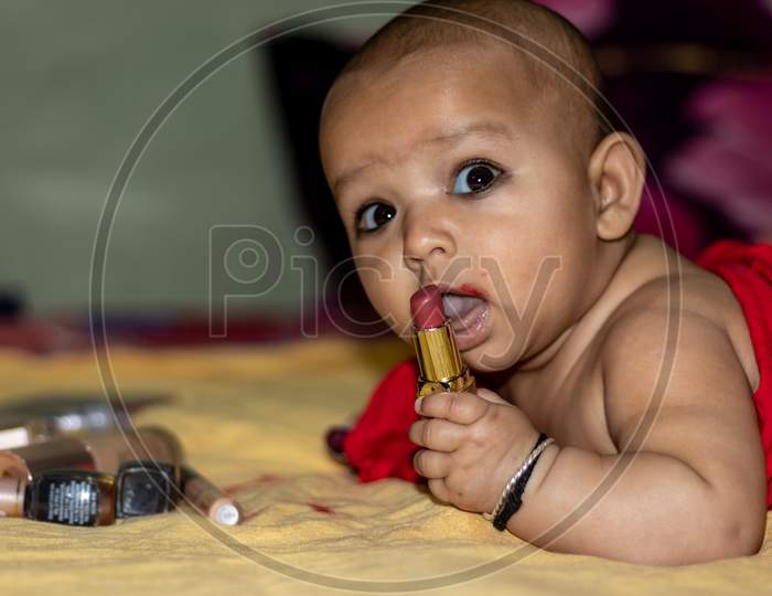 Baby Infant Cute Holding Lipstick With Blurred Background