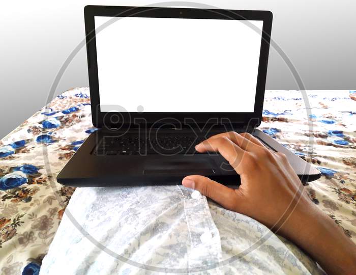 A Male Doing Work On Black Laptop Lying Down On Bed White Screen Mockup For Work From Home