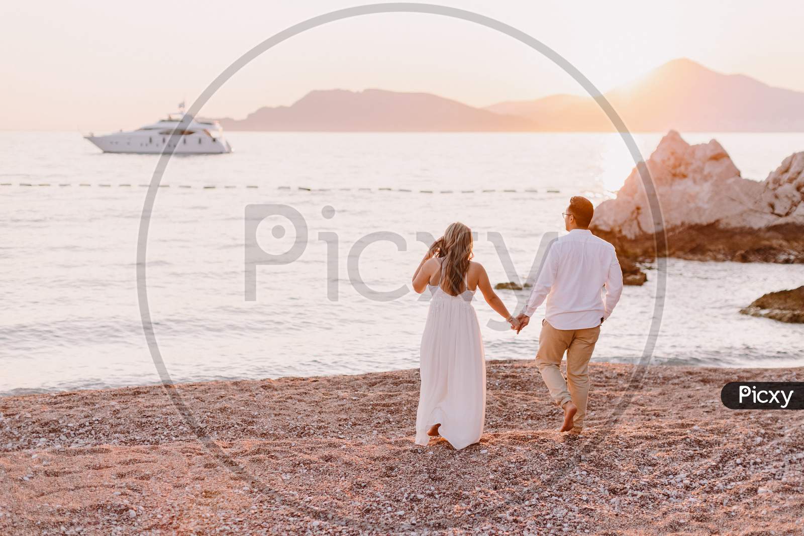 Couple Relax On Beach At Sunset With Yacht View