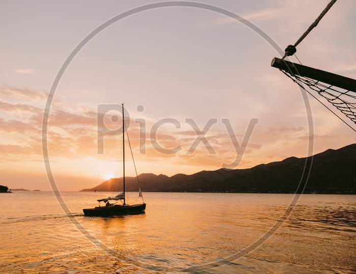Yacht Sailing At Sunset In Sea With Mountains View