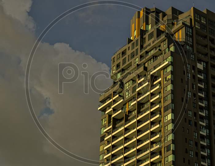 A Modern Apartment Building Below A Cloudy Sky In Thailand