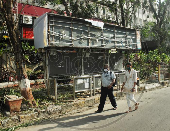 People walk past a damaged bus stop, after cyclone Nisarga made its landfall on June 3, on the outskirts of the city, in Mumbai, India, June 5, 2020.