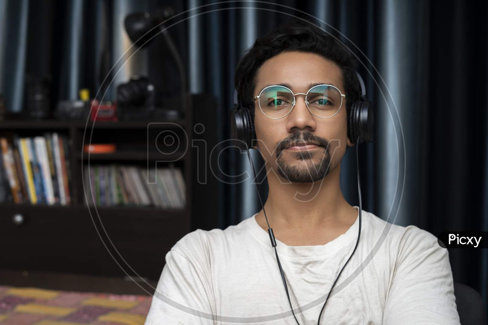 Young Indian Boy Wearing Glasses And Headphones Looking Into The Camera And Smiling
