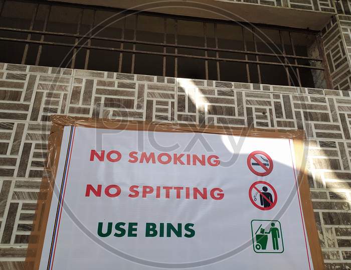 A display board of No Smoking, No spitting and use bins on the wall.