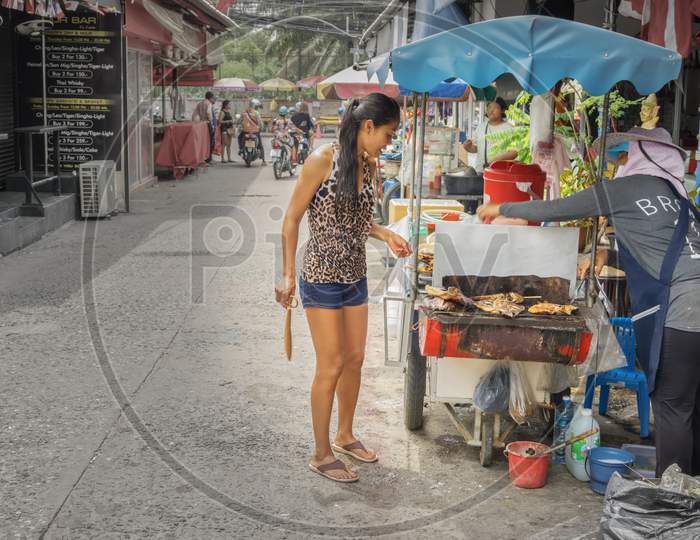 Pattaya,Thailand - April 17,2018: Soi Made In Thailand A Thai Woman Is Buying Some Traditional Food On The Street.