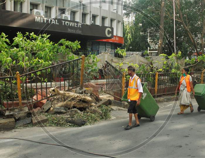 BMC workers walk past an uprooted pavement railing, after cyclone Nisarga made its landfall on June 3, on the outskirts of the city, in Mumbai, India, June 5, 2020.