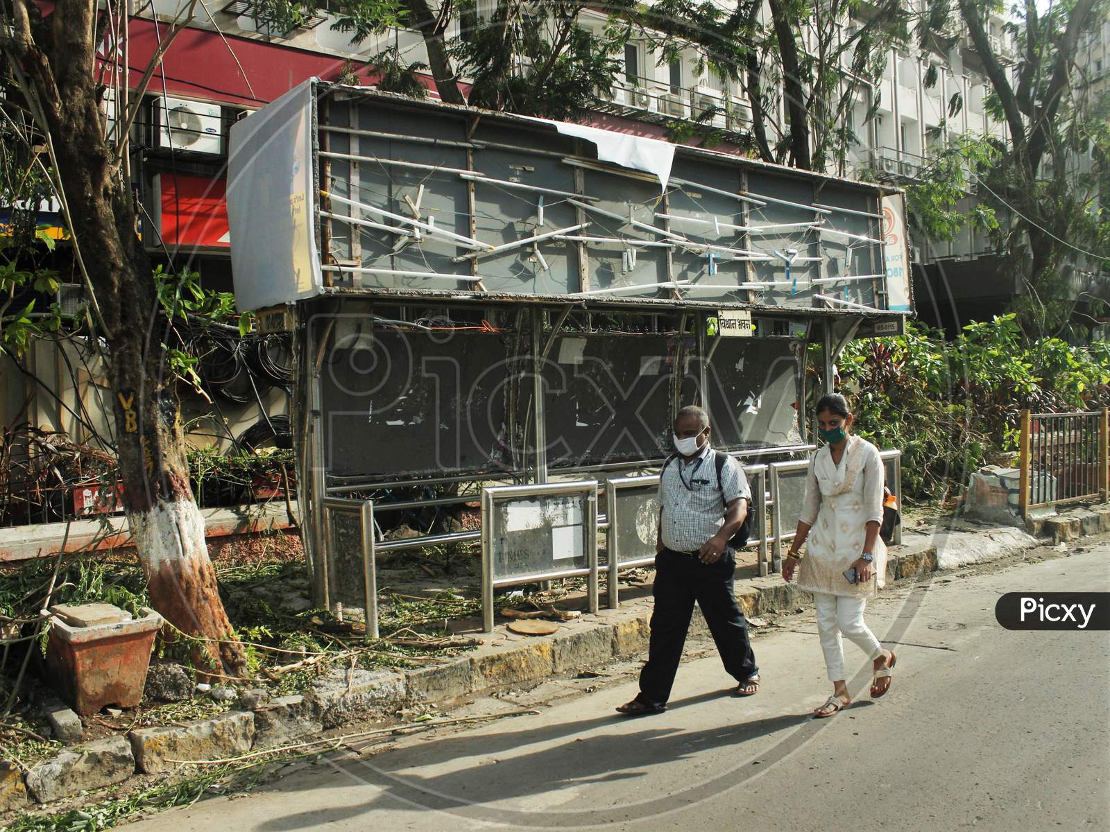 People walk past a damaged bus stop, after cyclone Nisarga made its landfall on June 3, on the outskirts of the city, in Mumbai, India, June 5, 2020.