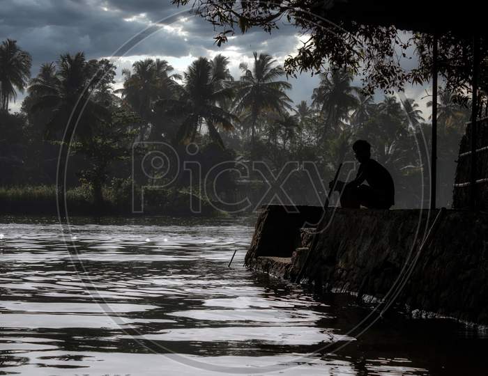 A Scenic View Of A Man Sitting By The Backwaters Situated In Allepey Town Located In Kerala State