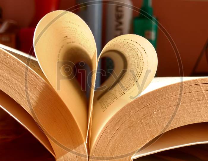 Close-Up Of The Book Opened, Which The Book Sheet Rolled Into A Heart Shape Selective Focus And Shallow Depth Of Field