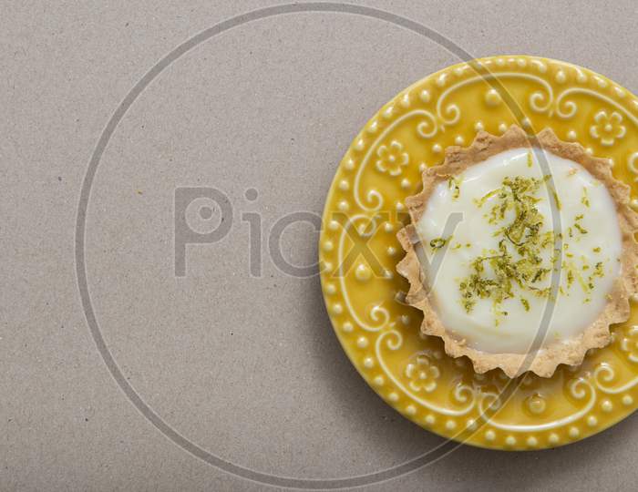 Top View Of Lemon Tart On A Beautiful Yellow Vintage Plate.