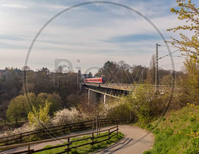 A Red Train Is Running Over An Old Bridge On A Spring Day In Germany