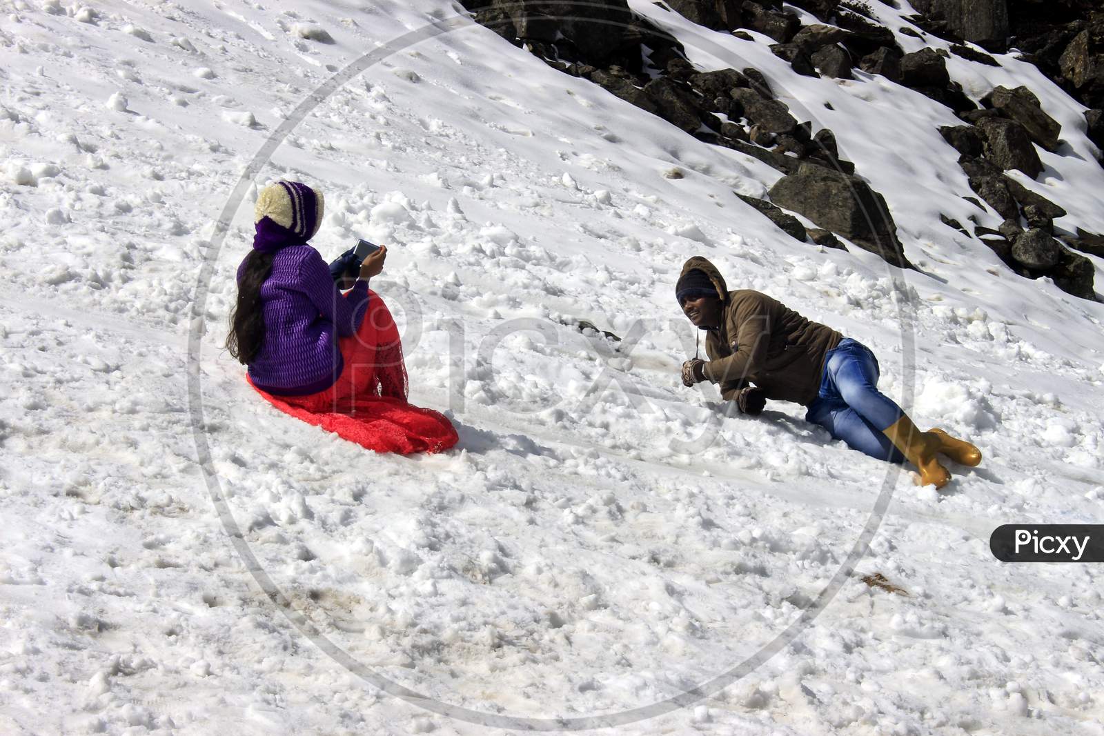People clicking photos by sitting on a Snow Capped Mountain in Sikkim