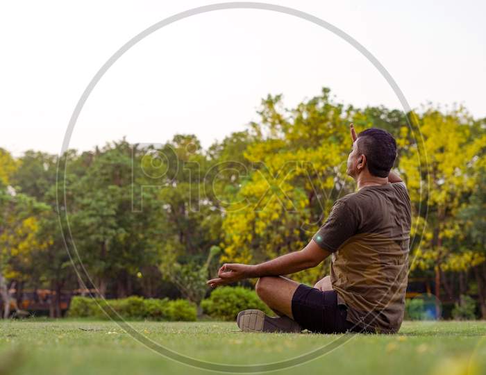 Mid-Aged Man Doing Yoga In A Park Covered With Trees, Anulom Vilom Pranayam.