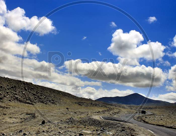 A Single Lane Road in Sikkim with Mountains and Huge Clouds