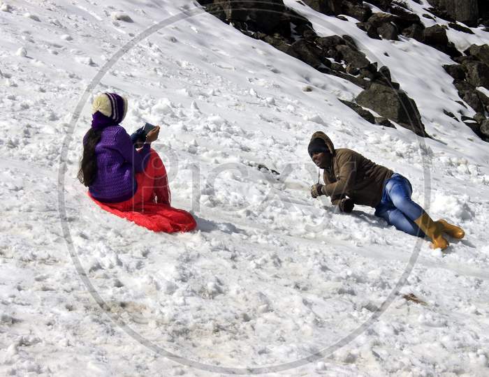 People clicking photos by sitting on a Snow Capped Mountain in Sikkim