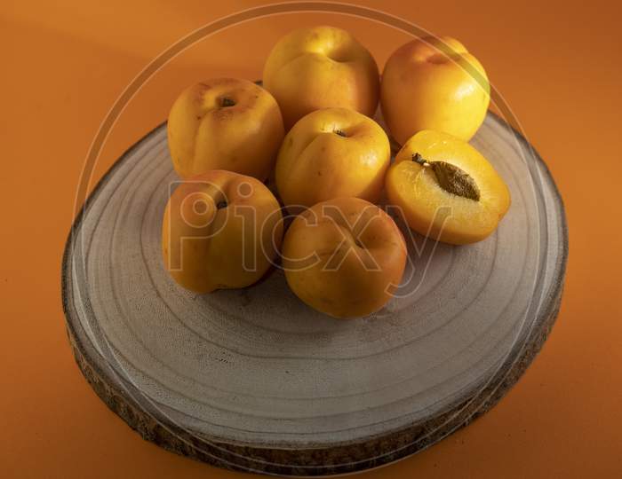 Peach on a wooden dish and an orange background.
