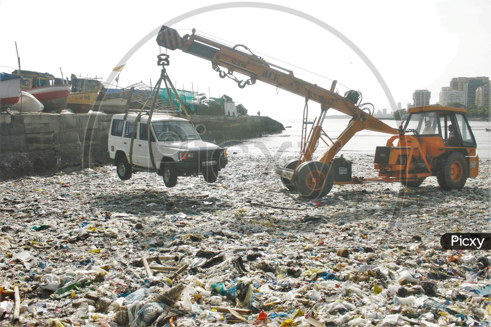A car parked in between the boats, is being lifted by a crane from a dock and taken to the road via the beach covered with plastic waste, in Mumbai, India on June 5, 2020.