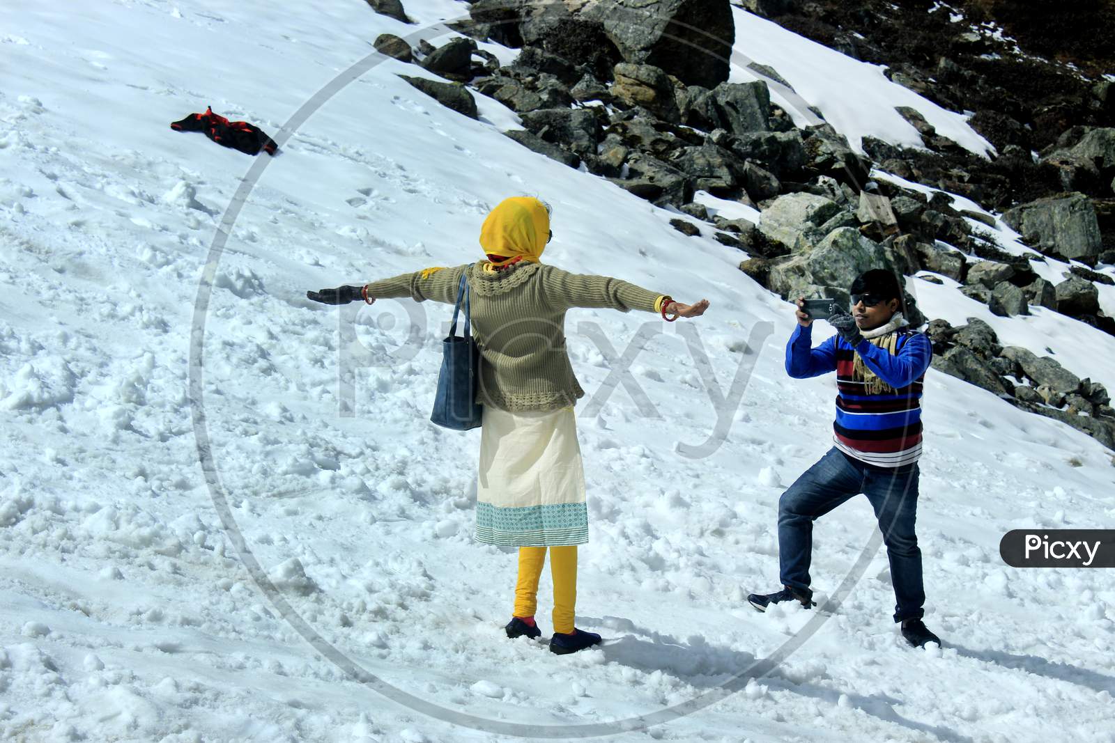 Tourists clicking photos by sitting on a Snow Capped Mountain