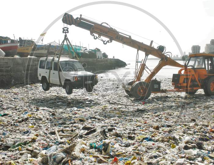 A car parked in between the boats, is being lifted by a crane from a dock and taken to the road via the beach covered with plastic waste, in Mumbai, India on June 5, 2020.