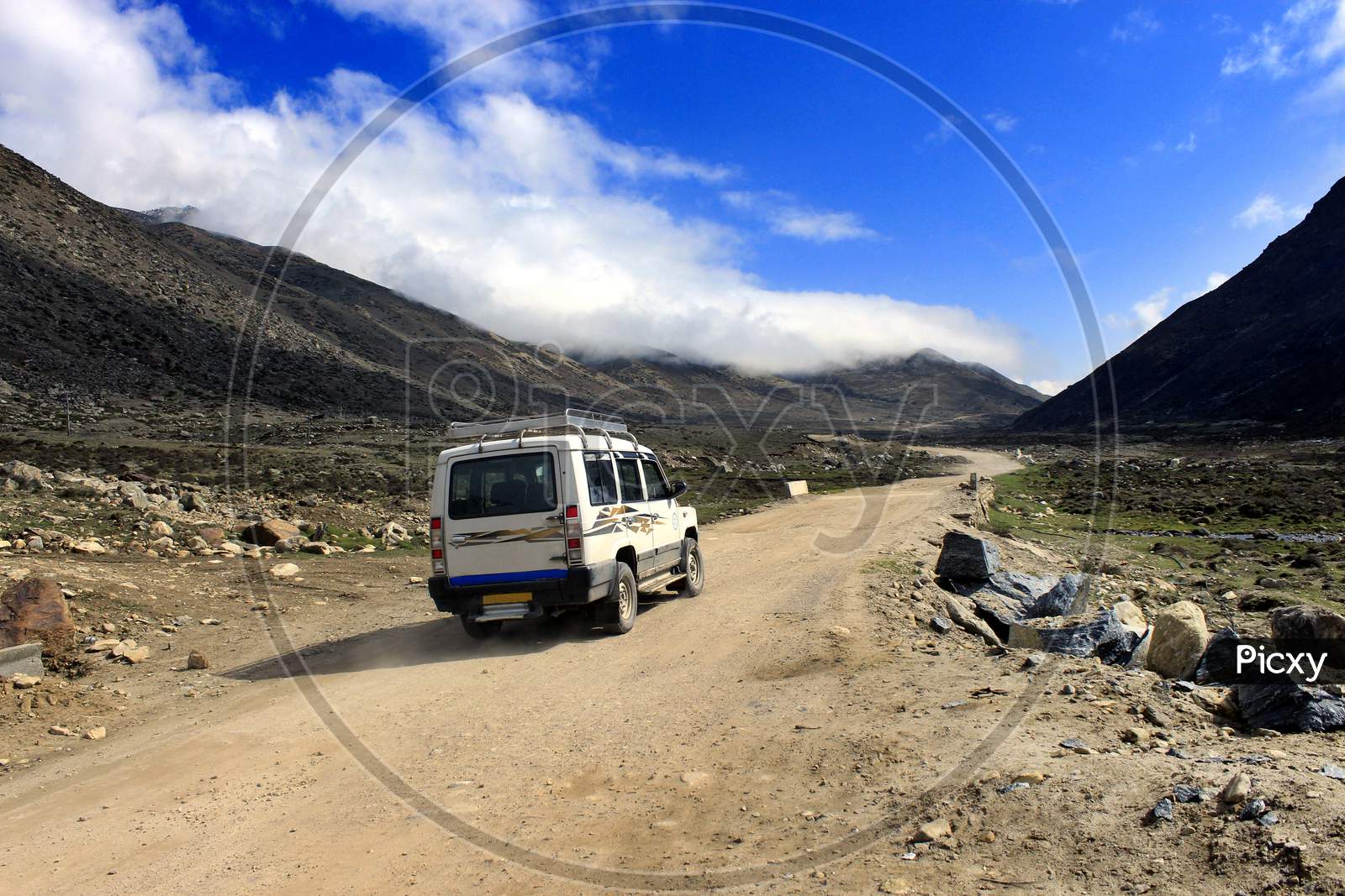A Vehicle moving on a Path with mountains of Sikkim in the Background