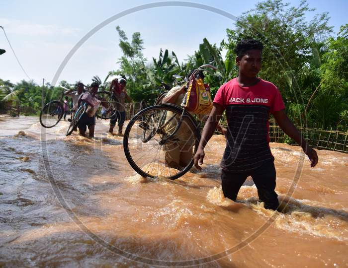 Villagers Carry Their Bicycle  As  They Wade Through A Flooded area At  Pramila Village Near Kampur In Nagaon District Of Assam On June 7,2020.