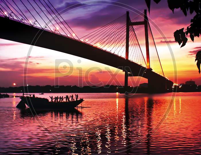 India, Kolkata, West Bengal. Silhouette Of Bridge And Boat