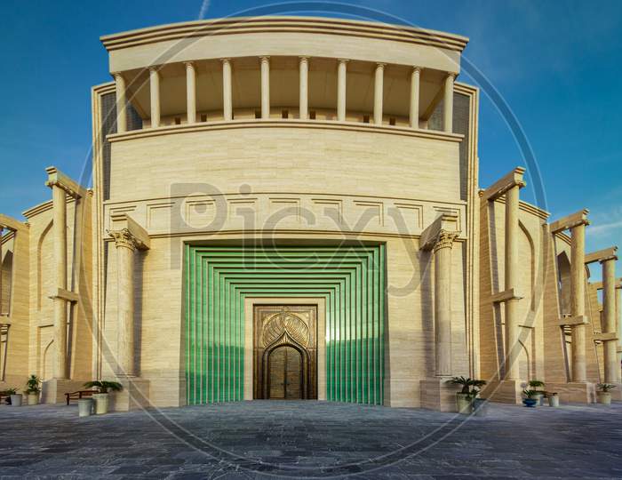 The amphitheater in Katara Cultural Village, Doha Qatar panoramic view in daylight from outside showing the main gate with clouds in the sky in background.