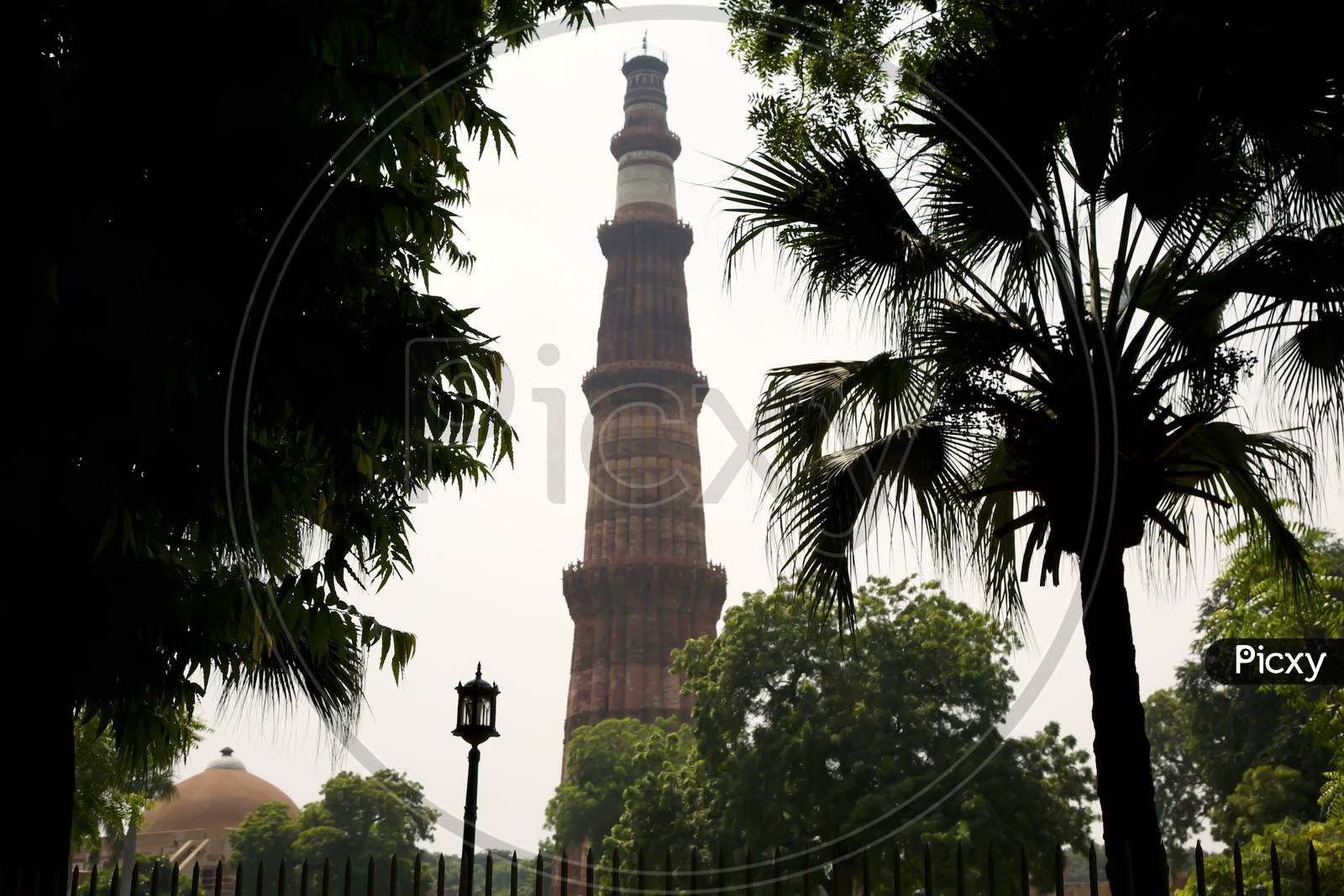 A View Of The Minar Through The Trees, The Combination Of Man Made And Natural Makes A Beautiful Place In India