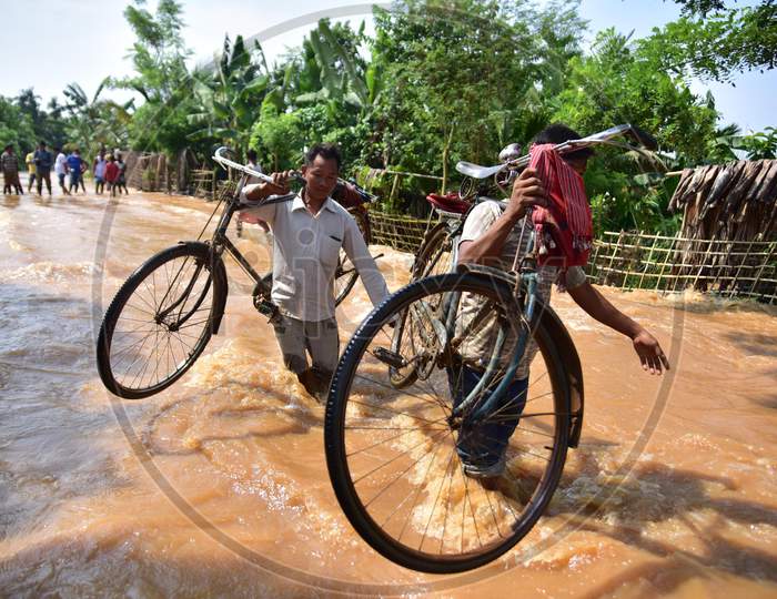 Villagers Carry Their Bicycle  As  They Wade Through A Flooded area at  Pramila Village Near Kampur In Nagaon District Of Assam On June 7,2020.