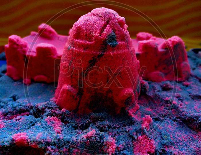 House of colorful sand or clay on a yellow background.