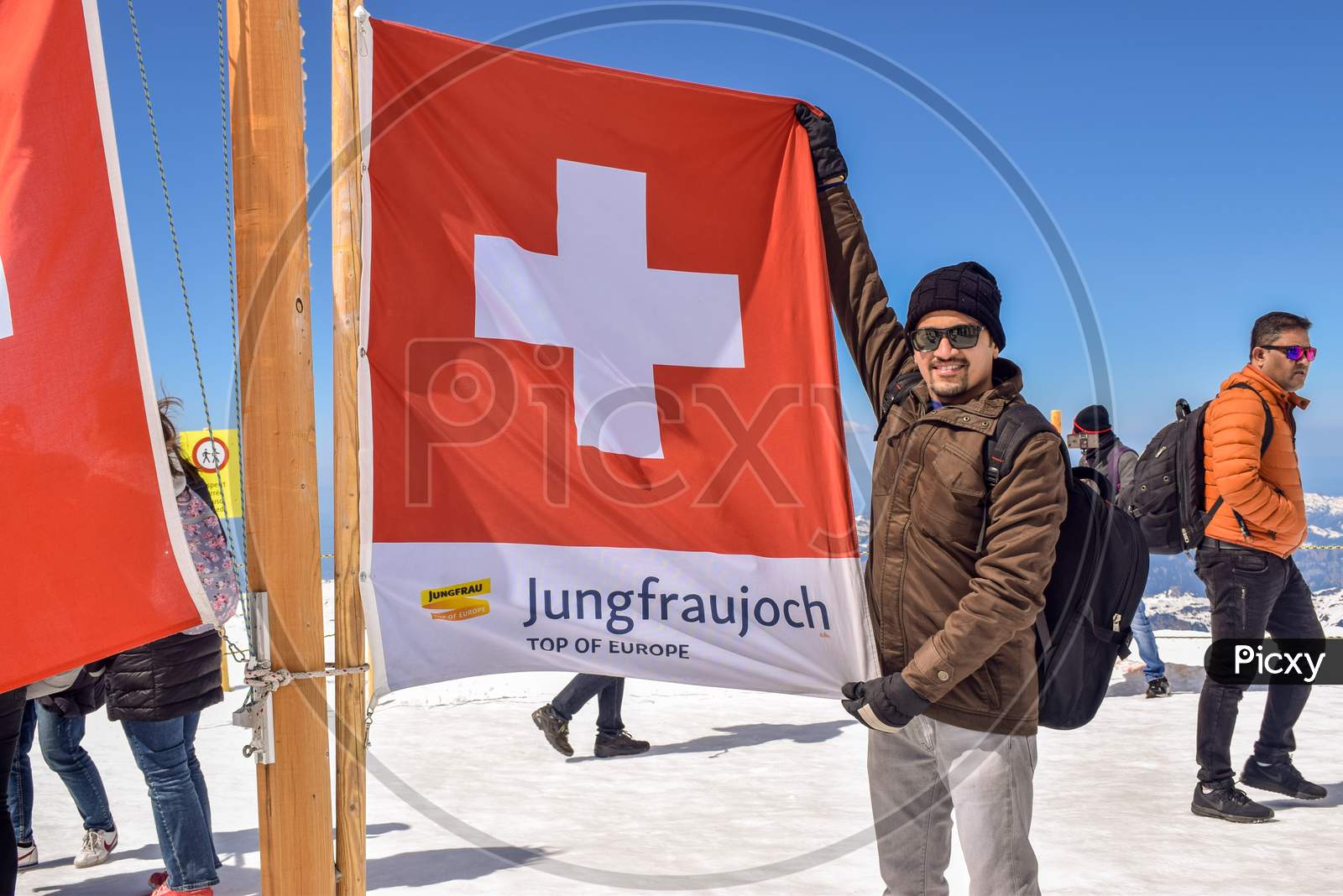 Jungfraujoch / Switzerland : April 20, 2019: Man Holding Flag of Switzerland hoisted on Highest Mountain Peak in Europe known as Jungfrau. It is the most visited place by tourists