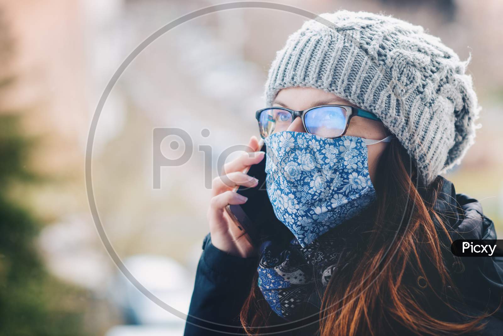 Phoning woman with handmade cloth face mask. Due to the lack of respirators and masks, the inhabitants of many countries sew them on their own.