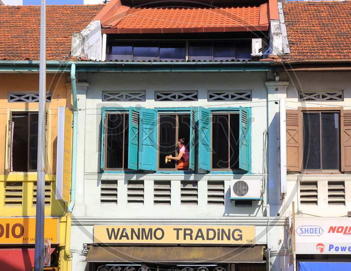A citizen cleans the window of his shop building in the morning.
