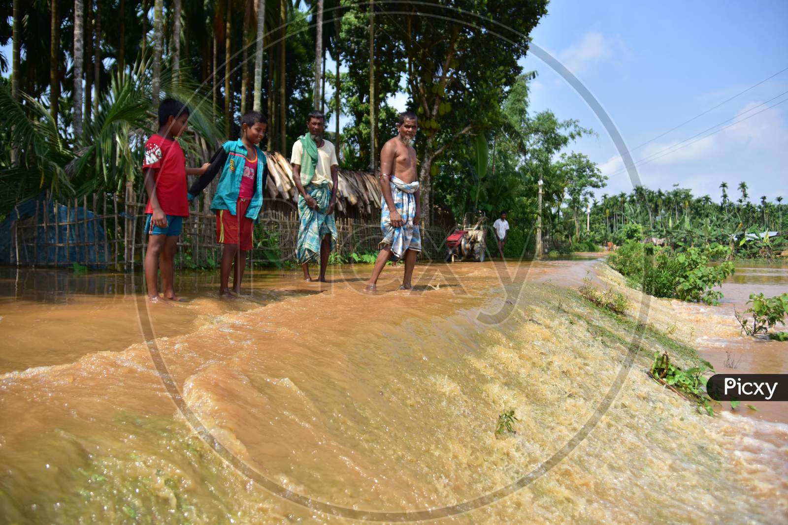 Villagers  Wade Through A Flooded Road At  Pramila Village Near Kampur In Nagaon District Of Assam On June 7,2020