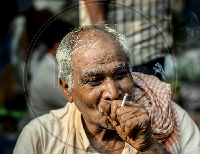 New Delhi, India - June 12, 2018 : Asian old man smoking in traditional style  despite Smoking being Injurious to health. Indian Labour works on very low daily wages