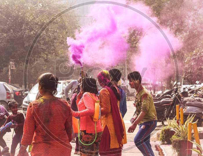 New Delhi, Delhi / India - March 04, 2019: Children playing with colorful smoke and celebrating the festival of holi in India.