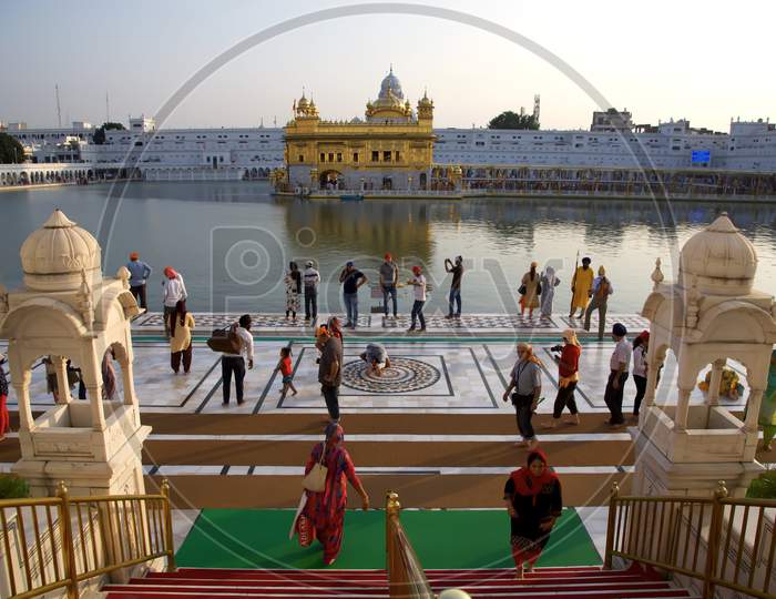 Steps Leading To The Water'S Edge Opposite Harmandir Sahib, Looking Down The Steps And Across The Water At Harmandir Sahib. Visitors Mill About.